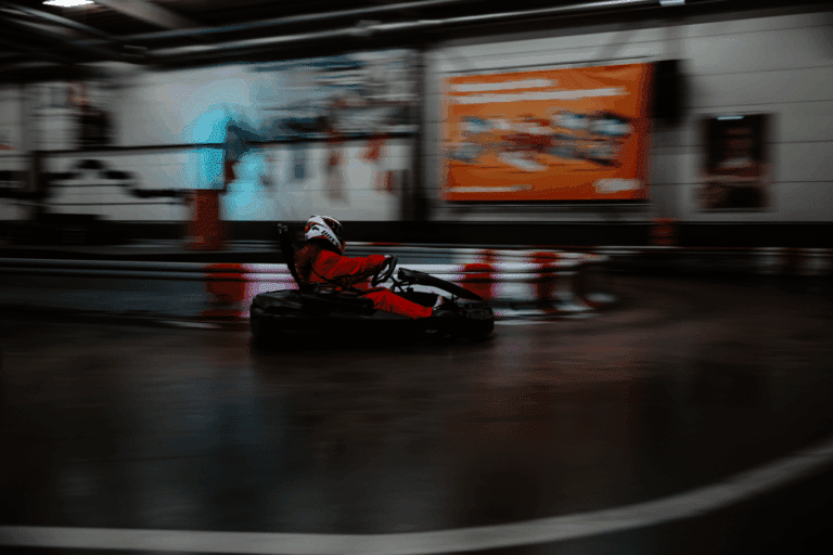 Ein Fahrer im roten Overall in einer Kurve von hinten auf der Rennstrecke im Kartcenter Cologne, Kartfahren Köln.