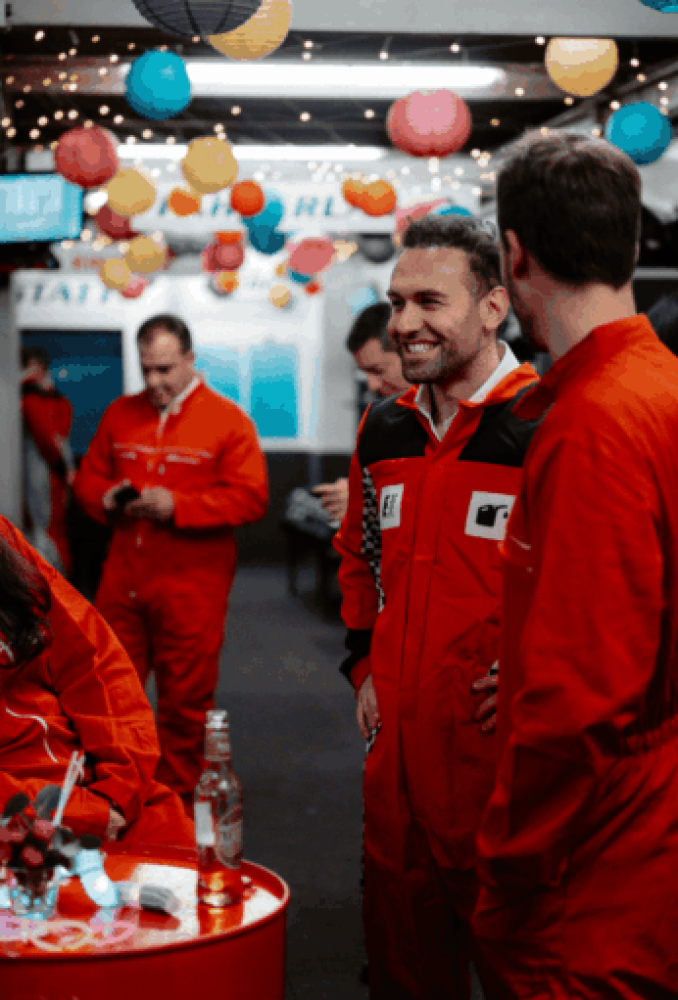 Mehrere Personen in roten Rennoveralls unterhalten sich im Kartcenter Cologne über das Kartfahren Köln.